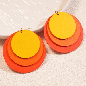Close-up of triple layered geometric wooden earrings with yellow orange red gradient