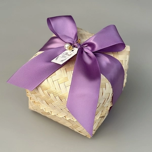 Macro detail of square bamboo gift box with purple satin bow and decorative pearl