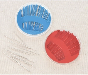 Close-up of circular sewing needle cases in red and blue on a beige canvas surface