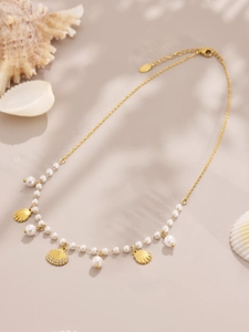 Detail of 18K gold shell necklace with small pearls and shell charms in warm sunlight