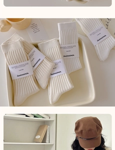 Close-up of white ribbed crew socks with packaging and a brown vintage newsboy cap