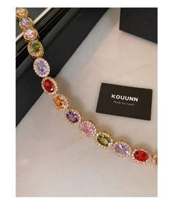Macro shot of oval colorful gemstones on gold bracelet with sparkling zircon halo setting