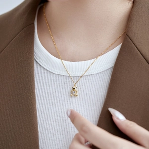 Detail shot of a delicate gold S925 silver necklace featuring a sparkling crystal bear pendant