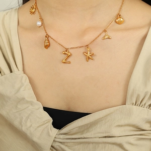 Gold bamboo letter necklace with sea star shells and pearls on a female model