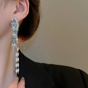 Detailed close-up of butterfly earrings with long pearl tassels and crystal accents