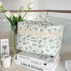 Detail of green floral quilted cotton makeup bag with brand label and top handle