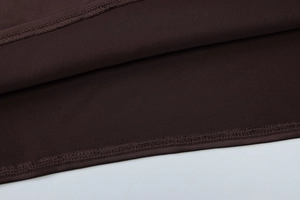 Gros plan détaillé du tissu marron de la robe montrant les coutures à double aiguille