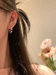 Close-up of minimalist silver hoop earring worn by a model in a lifestyle setting