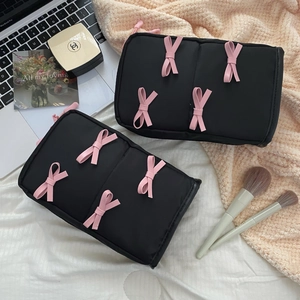 Detail view of two black makeup bags with pink bows in a cozy desk lifestyle setting