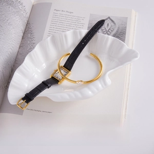 Detail of 18K gold stainless steel bangle with marquise zircon next to classic leather watch