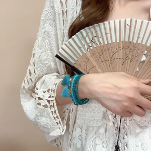 Close-up of bohemian multilayer beaded bracelet with turquoise stones and blue tassels