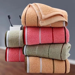 Thick soft cotton towels in pink, orange, and teal stacked in a bathroom setting