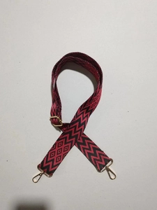 Detail eines rot-schwarzen geometrischen Web-Schultergurts mit goldenen Metallhaken