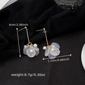 Detail view of flower earrings with white petals, pearls and gold tassel on black silk