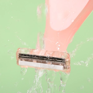 Pink manual women's shaver head with multiple blades under flowing water stream