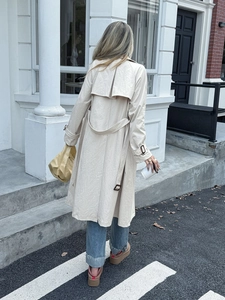Vista posteriore trench beige di media lunghezza con mantellina posteriore e cintura