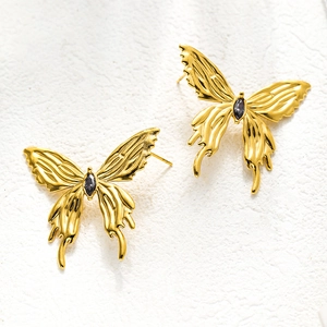 Detailed view of golden butterfly stud earrings with antique texture and dark gemstone