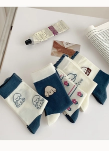 Détail de chaussettes en coton bleu et beige avec motifs de chiens et de fleurs