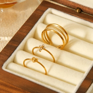 Three-piece gold ring set with heart and star charms in a premium wooden jewelry box