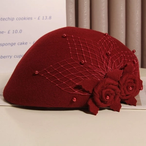 Detail of burgundy wool beret featuring floral mesh veil and white pearl accents
