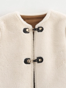 Détail de veste en peau lainée avec lanières en cuir noir et boucles en métal doré