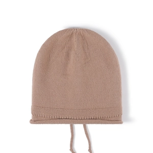 Pink knitted baby hat with soft chin straps and ruffled edges on white background