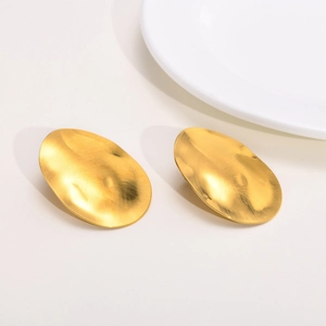Detail of golden stainless steel hoop earrings with hammered texture and modern finish