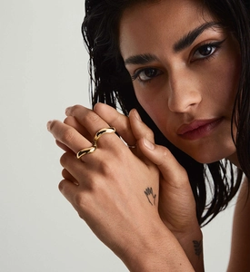 Detailed view of an irregular wavy gold ring with a polished finish worn by a model