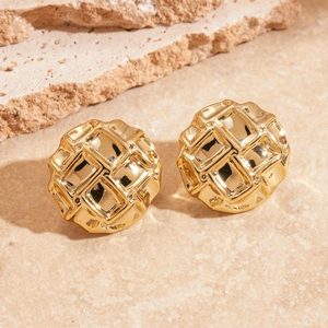 Gros plan de boucles d'oreilles dorées géométriques avec texture en relief sur pierre