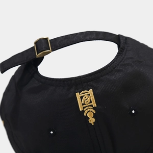Dettaglio del cappellino nero con ricamo dorato e fibbia di regolazione in metallo bronzo