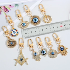 Golden Evil Eye keychains with crystals and assorted charms on a white background