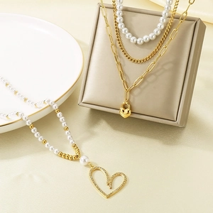 Detailed macro of a multi-layer gold chain necklace with a rhinestone heart pendant and pearls