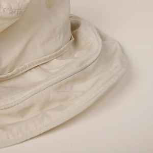 Macro detail shot of quick-dry sun hat showing precise stitching and beige fabric texture.