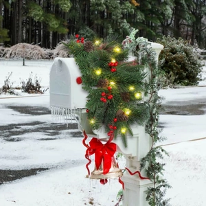 Christmas pine cone wreath with LED lights, red berries, and bow on a white mailbox