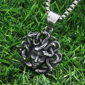 Detailed close-up of a Medusa snake head pendant in stainless steel on green grass