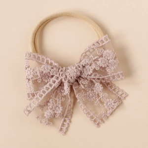 Detail of baby nylon headband featuring a beige floral lace bow with delicate embroidery