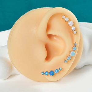 Detailed view of gold ear crawlers featuring five graduated opal stones on ear model