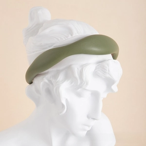 Detailed texture of avocado green faux leather padded headband on a classical sculpture