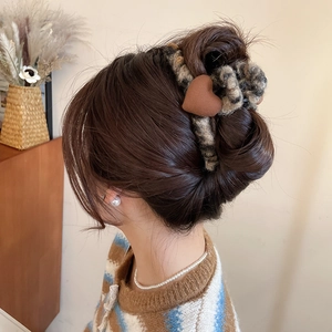 Détail d'une pince à cheveux motif léopard et cœur en velours pour chignon haut