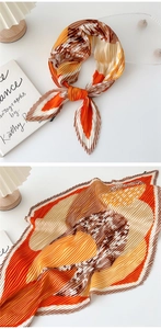 Detailed view of pleated silk scarf featuring orange and beige geometric print patterns