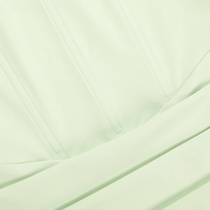 Détail macro des coutures et texture du tissu vert clair lisse sur une mini robe ajustée