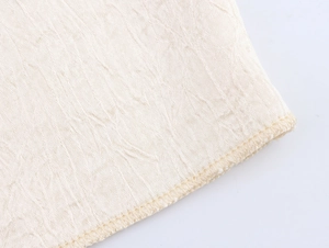 Dettaglio macro del tessuto in raso beige con trama a pieghe e cucitura overlock fine