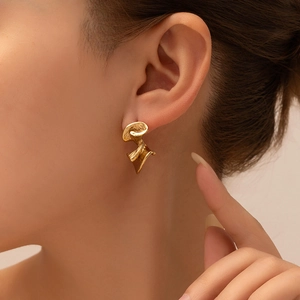 Macro view of gold stainless steel earrings featuring abstract pleated geometric textures