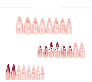 Detail of pink stiletto press-on nails with 3D bows, pearls, and heart star patterns