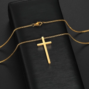 Detailed view of golden cross pendant on box chain over black jewelry box display