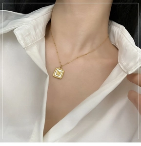 Detail of gold butterfly necklace with mother of pearl pendant on a model wearing white