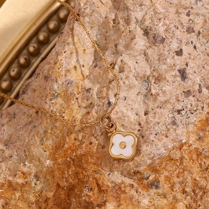 Macro shot of 18K gold plated necklace with white shell flower pendant on mineral stone