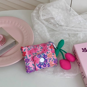 Floral fabric coin purse with plush cherry keychain accessory in an aesthetic setting