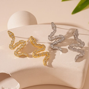 Snake shape zircon earrings in gold and silver plating displayed on stone props