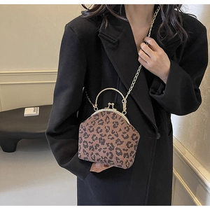 Leopard print shell bag with golden metal frame and chain strap shown on black blazer